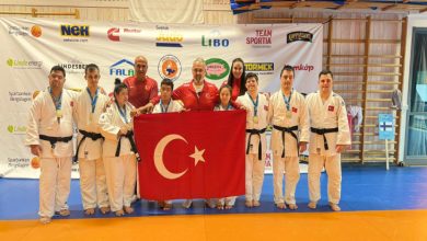 Down Judo Milli Takımı ile teknik kadro Türk Bayrağı tutarak poz veriyor.