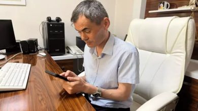 Görme engelli Avukat Bünyamin Gürsaçtı ofis masasında telefon kullanıyor.