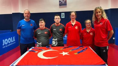 Down Masa Tenisi Erkek ve Kadın Milli Takımı sporcularımız, tenis masası üstünde bulunan Türk Bayrağı üzerine kazanılan madalyaları koyarak poz veriyor.