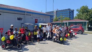 Görselde, engelli bireylerin kullandığı akülü araçların renkli balonlarla süslendiği görülmektedir. Engelli bireyler yan yana dizilerek bir tür konvoy için hazırlık yapmaktadır.