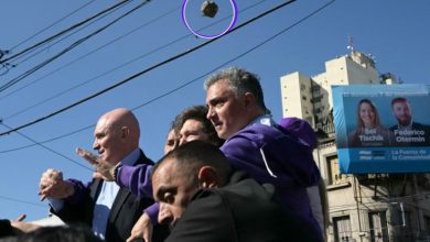 Görselde, kalabalık bir ortamda siyasetçi ya da yetkili konumunda olduğu anlaşılan bir grup insan yer alıyor. Ön planda birkaç erkek şahıs dikkatlice etrafa bakarken yukarıdan bir taşın havada uçmakta olduğu an objektife yansımış. Taş mor bir daire ile işaretlenmiş. Arka planda apartmanlar, elektrik telleri ve seçim afişleri görünüyor. Afişte “Sol Tischik” ve “Federico Otermin” isimleri okunabiliyor. Görsel, Arjantin Devlet Başkanı Javier Milei’nin seçim kampanyası sırasında taşlı saldırıya uğradığı anı belgeleyen bir fotoğraf niteliğinde.