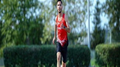 Görselde, kırmızı formasıyla pistte koşan atlet Çağatay Çelik görülüyor. Arka planda yeşil çalılar ve ağaçlar yer alıyor, sporcu odaklı ve hareket hâlinde çekilmiş bir fotoğraf.