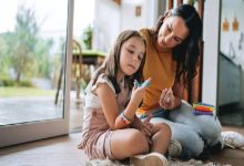 Görselde, otizm tanılı küçük bir kız çocuğu annesiyle birlikte, parmağına taktığı oyuncakla mental ve fiziksel gelişim egzersizi yapıyor.