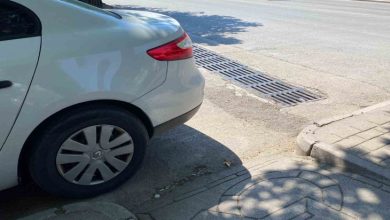 Beyaz otomobil kaldırım rampasının önünde park edilmiş.