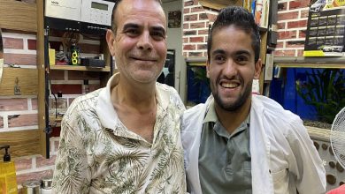 Görselde, bir berber dükkanında Ayhan Deliorman ve zihinsel engelli birey Faruk Taymura yan yana ayakta duruyor.