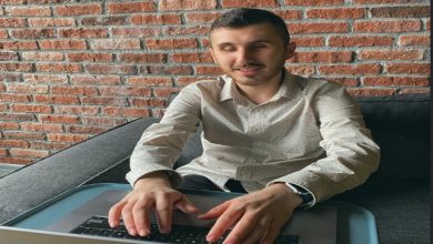 Görselde Binclusive sosyal girişimin kurucusu Atakan Nalbant, önünde yer alan dizüstü bilgisayarı bir masa üzerinde kullanıyor.