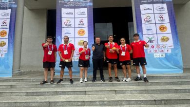 Türkiye Özel Sporcular Spor Federasyonu Başkanı Birol Aydın, spor salonu önünde milli sporcularla birlikte poz veriyor.