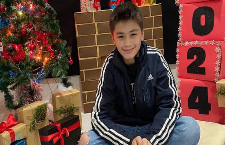 Yeni yıl temalı süslemelerle dekore edilmiş bir ortamda, Murat Duha Yıldız yere oturmuş halde gülümsüyor.