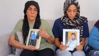 Fotoğrafta iki kadın, ellerinde çerçeveli fotoğraflar tutarak oturuyor; yüzlerinde derin bir üzüntü ifadesi var. Bu kare, yakınını kaybetmiş bir ailenin acısını ve adalet arayışını yansıtıyor.