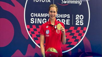 Milli para yüzücü Defne Kurt, kazandığı altın madalyayı elinde tutarak şampiyona sponsorlarının adının yer aldığı stant önünde poz veriyor.