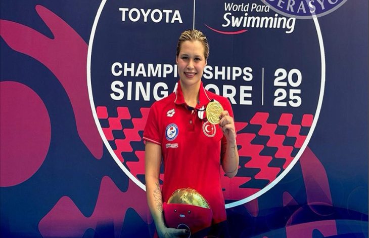 Milli para yüzücü Defne Kurt, kazandığı altın madalyayı elinde tutarak şampiyona sponsorlarının adının yer aldığı stant önünde poz veriyor.