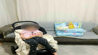 Fotoğrafta bir ev ortamında, bebek arabasına benzer bir koltukta oturan bir kişi yer alıyor. Yüzü bulanıklaştırılmış. Arka planda bir koltuk üzerinde çocuk bezi ve bakım malzemeleri görülüyor. Görüntü, yardım ya da bağış temalı bir durumu yansıtıyor.