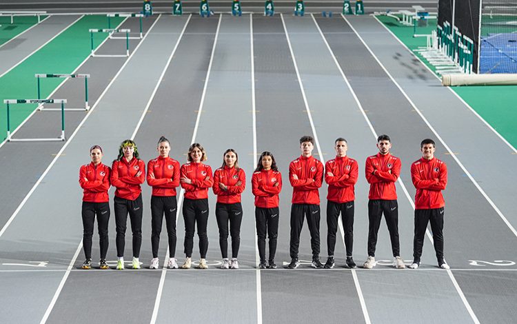 Özel Sporcular Atletizm Milli Takımı, gri olimpiyat pistinde yan yana durarak poz veriyor.