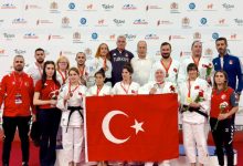 Milli Para Judocularımız, teknik heyetle birlikte Türk Bayrağı tutarak poz veriyor.
