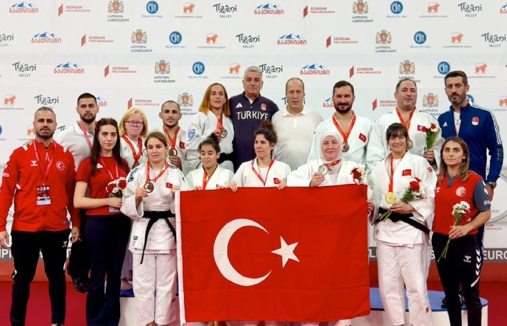 Milli Para Judocularımız, teknik heyetle birlikte Türk Bayrağı tutarak poz veriyor.