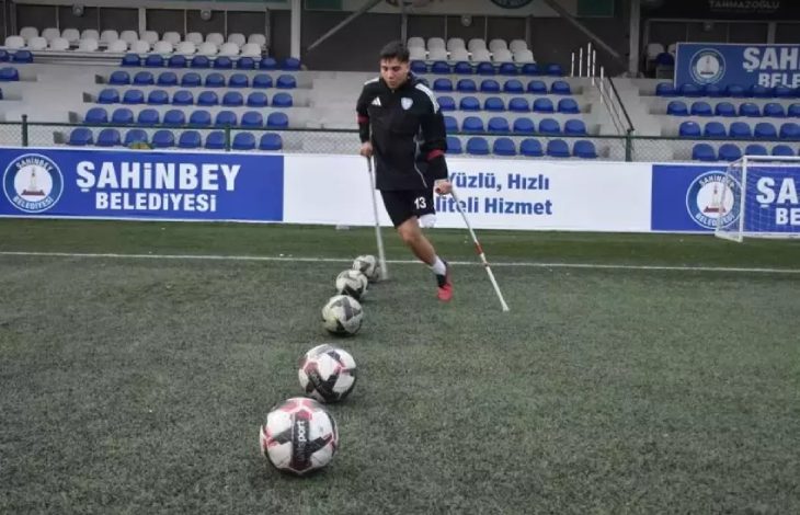 Ampute futbolcu Alaaddin Kazcı, çim sahada önünde bulunan beş topa vuruş hazırlığı yapıyor.