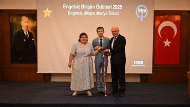 Görselde, “Engelsiz Bilişim Ödülleri 2025” töreninde sahnede üç kişi yer alıyor. Ortadaki kişi ödül alırken diğer iki kişi yanında duruyor. Arkada “Engelsiz Bilişim Medya Ödülü” yazılı bir perde, sol tarafta Atatürk portresi ve sağda Türk bayrağı bulunuyor.