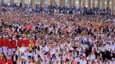 Görselde Anıtkabir’de toplanmış çok büyük bir kalabalık görülüyor. Katılımcıların çoğu beyaz tişört giymiş ve bazılarının elinde Türk bayrakları var. Ön sıralarda kırmızı kıyafetli mehteran takımı da dikkat çekiyor. Kalabalık, birlik ve dayanışma içinde bir etkinlik için bir araya gelmiş görünüyor. Arka planda Anıtkabir’in sütunları yer almakta.