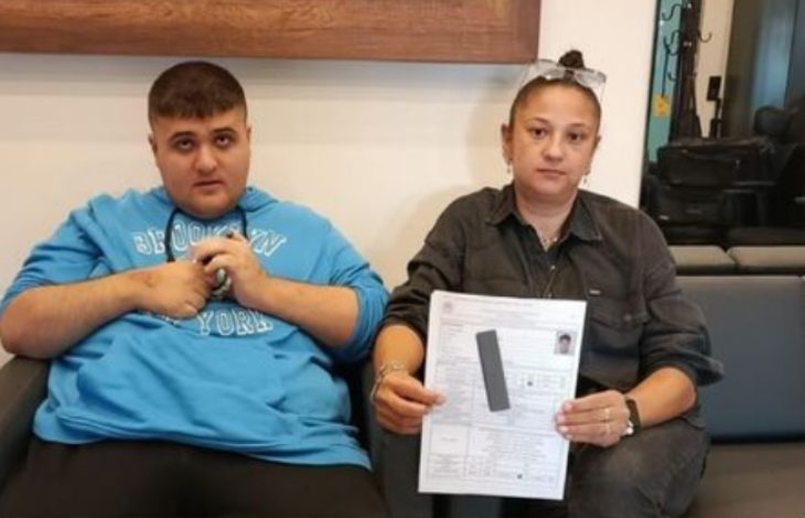 Görselde iki kişi bir koltukta yan yana oturuyor. Soldaki genç mavi bir sweatshirt giymiş, sağdaki kadın ise elinde engelli raporu belgesi tutuyor. Belgenin bazı bölümleri gizlenmiş. Arka planda iç mekân detayları görülüyor.