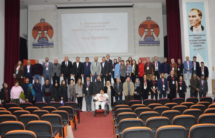 Fotoğrafta, bir konferans salonunda çekilmiş kalabalık bir grup görülüyor. Sahnenin arkasında “4. Uluslararası Katılımlı Orta Karadeniz Engelli ve Yaşlı Sağlığı Kongresi – Hoş Geldiniz” yazılı bir sunum yansıtılmış. Sahnenin her iki yanında “Havza Belediyesi” logoları ve Mustafa Kemal Atatürk’ün portresi yer alıyor. Katılımcılar ön sırada ve sahne üzerinde grup halinde poz vermiş; aralarında kadınlar, erkekler ve bir tekerlekli sandalye kullanan kişi bulunuyor. Arka plandaki kırmızı perde ve salonun turuncu-siyah renkli koltukları dikkat çekiyor.