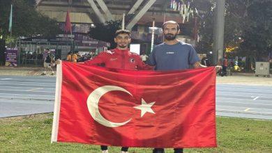 Milli Atlet Mehmet Emin Eğilmez antrenörü ile birlikte Türk Bayrağını tutarak poz veriyor.