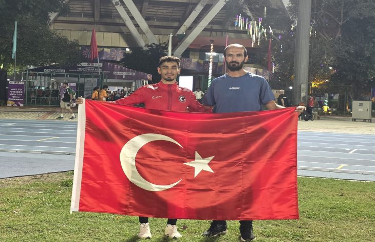 Milli Atlet Mehmet Emin Eğilmez antrenörü ile birlikte Türk Bayrağını tutarak poz veriyor.