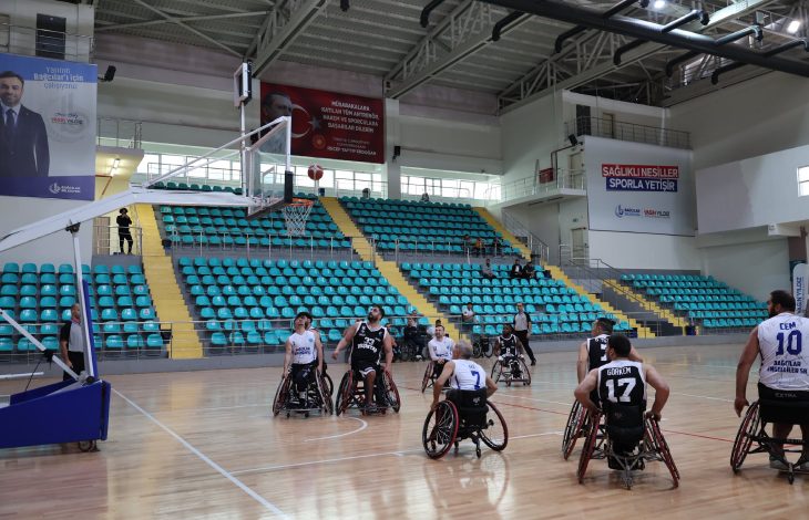 Bağcılar ve Beşiktaş Tekerlekli Sandalye Basketbol Takımı oyuncuları pota altında fileye girecek topa bakarken.