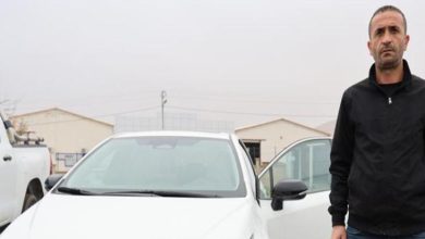 Fatih Tuğ beyaz renkli otomobilinin yanında ayakta duruyor.