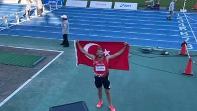 Milli Sporcumuz Yasin Süzen sırtında tuttuğu Türk Bayrağını havaya kaldırarak pistte poz veriyor.