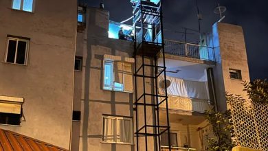 Fotoğrafta, çok katlı bir apartmanın dış cephesine sonradan eklenmiş bir engelli asansörü görülüyor. Gece çekilmiş görüntüde asansör kabini en üst kata yakın bir noktada, mavi ışıkla aydınlanmış şekilde duruyor. Binanın cephesi eski bir yapıyı andırıyor; açık balkonlar, perdeyle kapatılmış alanlar ve farklı tipte pencereler dikkat çekiyor. Asansörün metal iskeleti dar ve oldukça yüksek; bu da kullanımı sırasında ciddi riskler oluşturabilecek bir görünüm veriyor.