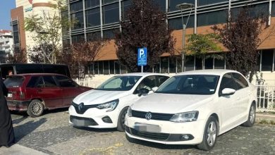 İki beyaz otomobil engelli park alanında bulunuyor.