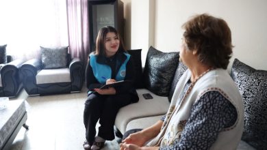 Uzman Psikolog Günay Duygu Ateş, yaşlı kadınla beraber koltukta oturarak iletişim kuruyor ve not alıyor.