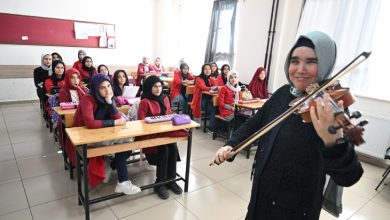 Görme engelli öğretmen Zeynep Temirci, sıralarda oturan öğrencilerine keman çalıyor.