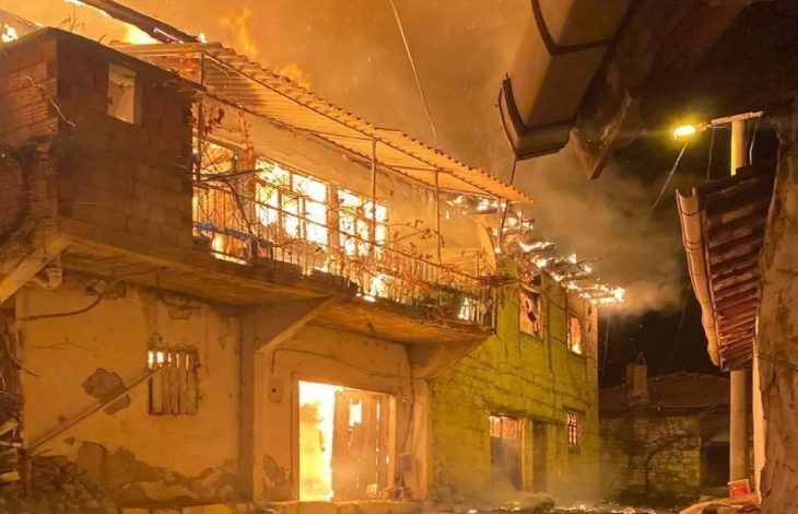 Alevler içinde yanan iki katlı köy evi.