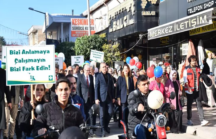 Kortej yürüyüşünde engelliler, yakınları ile yöneticiler ellerinde döviz ve balon tutarak bulunuyor.
