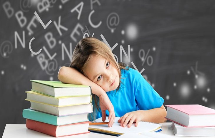 Görselde, masada kitaplar arasında oturan küçük bir çocuk görülüyor. Çocuk başını koluna yaslamış, önündeki deftere dalgın ve yorgun bir ifadeyle bakıyor. Arka planda ise tahtaya dağınık hâlde yazılmış harfler ve semboller yer alıyor; bu da öğrenme sürecindeki zihinsel karmaşayı çağrıştırıyor.