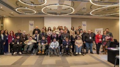 Bir konferans salonunda, Türkiye SMA Vakfı’nın düzenlediği seminer sonrası uzmanlar, aileler ve tekerlekli sandalye kullanan katılımcıların birlikte toplu fotoğraf çektirdiği görülüyor.