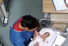 Hemşirenin küvöz içinde bulunan bebeğin yanında dururken çekilmiş görüntü.