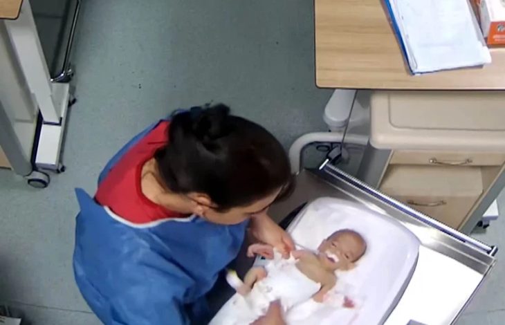 Hemşirenin küvöz içinde bulunan bebeğin yanında dururken çekilmiş görüntü.