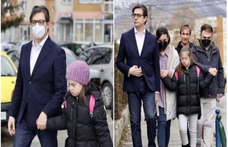 Yan yana iki kareden oluşan bir fotoğraf. Solda: Takım elbiseli bir adam, sokakta yürürken Down sendromlu küçük bir kızın elini tutuyor. Kız siyah montlu, pembe bere takıyor; okul yolunda gibi, yüzü ciddi. Adam koruyucu bir refleksle yanında. Sağda: Aynı kız bu kez ailesiyle birlikte yürüyor. Önde yine takım elbiseli adam, yanında yetişkinler ve arkalarında kız. Hepsi kalın montlu, sakin ama dikkatli adımlarla ilerliyor. Fotoğraf, bir çocuğun gündelik hayatında ailesinin desteğini ve birlikte yürüyüşünü sade, çarpıcı bir şekilde gösteriyor.