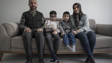 Gri tonlu bir salonda, bir kanepeye yan yana oturmuş dört kişilik bir aile. Anne ve baba iki yanda, aralarında iki çocuk; hepsi kameraya sakin, ciddi ve biraz yorgun bakıyor. Oda sade, sessiz ve durağan bir anın içine sıkışmış gibi.