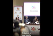 Bir konferans salonunda düzenlenen panelde üç konuşmacı masa başında oturuyor. Arkalarında “Cris contra el cáncer” logosu ve araştırma sunumunun yer aldığı bir ekran bulunuyor; ortam resmi ve akademik bir toplantıyı yansıtıyor.