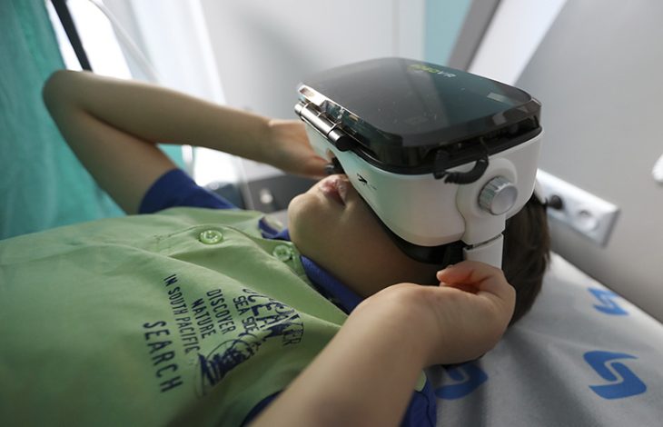 Uzanan erkek çocuk sanal gerçeklik gözlüğü kullanıyor.