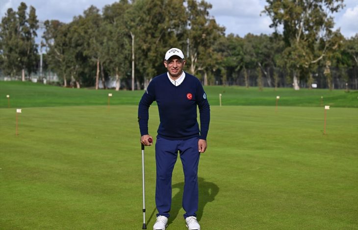Engelli sporcu Mehmet Kazan golf sahasında değnek tutarak ayakta poz veriyor.
