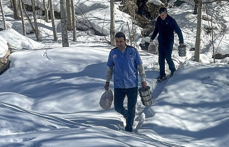Karlı arazide ilerleyen iki görevli, termos ve poşetlerle sıcak yemekleri özel gereksinimli ve yaşlıların evlerine ulaştırmak için yol alıyor.