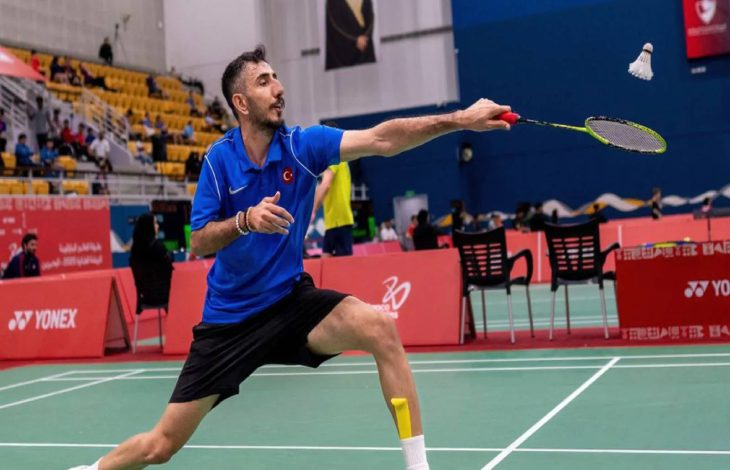 Milli para sporcu İlker Tuzcu raketiyle badminton topuna vuruşunda dizlerinin üstünde duruyor.