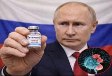 Takım elbiseli bir erkek, arka planda Rusya bayrağı önünde küçük bir flakonu kameraya doğru tutuyor. Flakonun üzerinde “ENTEROMIX – Cancer Vaccine” yazıyor. Görselin sağ alt köşesinde ise kanser hücrelerini temsil eden illüstratif bir mikroskobik görsel yer alıyor.