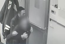 Bir güvenlik kamerası görüntüsünde, kapı önünde duran bir görevlinin öksüren bir kişiye arkadan sarılarak müdahalede bulunduğu görülüyor. Ortam kapalı bir alan; kişi boğulma anında yardım alıyor.