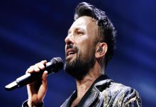 Tarkan elinde tuttuğu mikrofonla şarkı söylüyor.