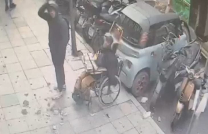 Kamera görüntüsünde düşen beton parçaları kaldırımda bulunuyor, yaralanan çocuk başını tutarken engelli satıcı yanında duruyor.